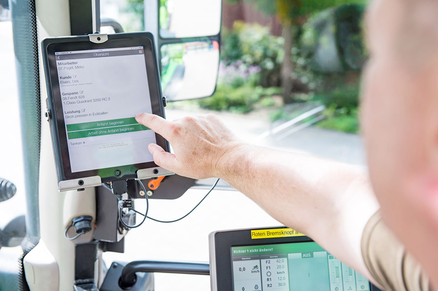 Ein Mann Bedient ein Ipad mit dem Programm in einer Landmaschine,