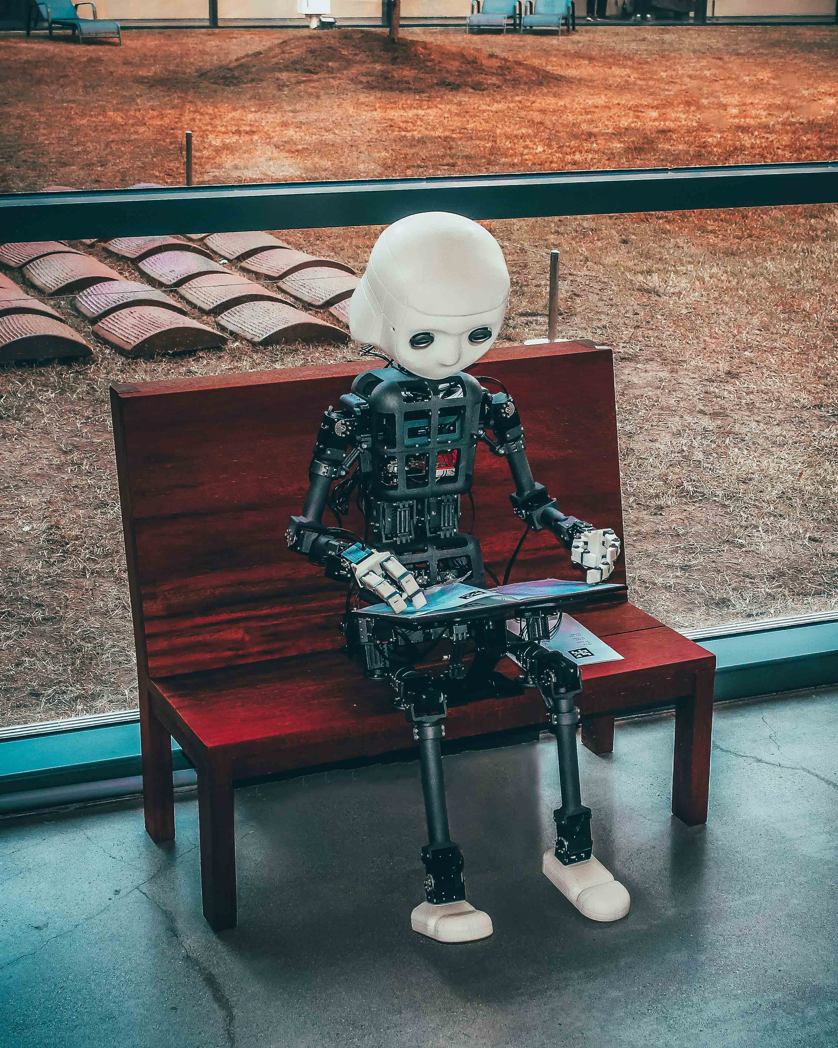 Ein Roboter, der auf einer Bank sitzt und durch eine Zeitung blättert.