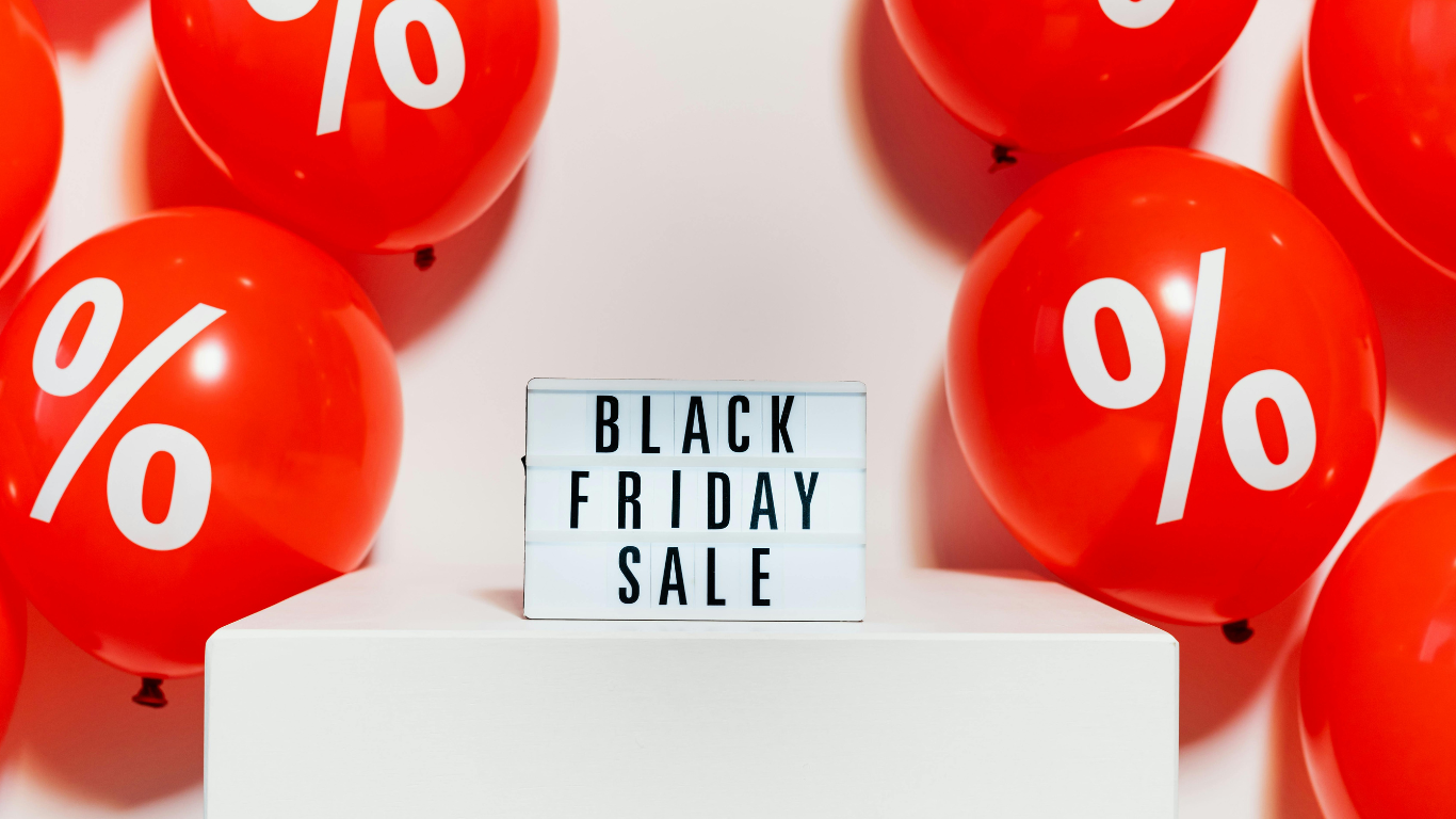 Schwarze Leuchttafel mit Aufschrift „Black Friday Sale“, umgeben von roten Luftballons mit Prozentzeichen – Symbolbild für Peak Season, Performance-Optimierung und stabiles Web-Hosting für E-Commerce-Shops mit TYPO3, Shopware 6, Magento Hyvä und Solr Integration.