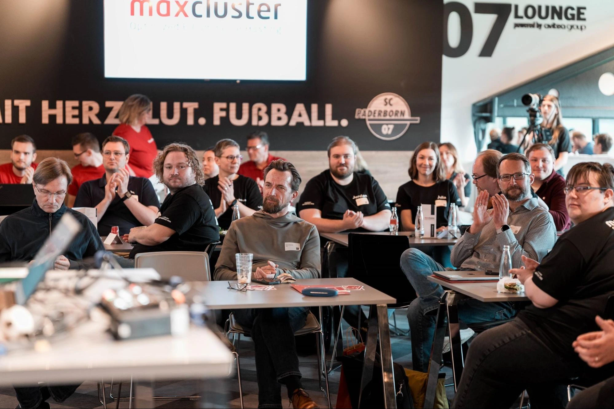 Teilnehmende verfolgen eine Session beim maxcluster-Partnertag 2026 in der Home Deluxe Arena