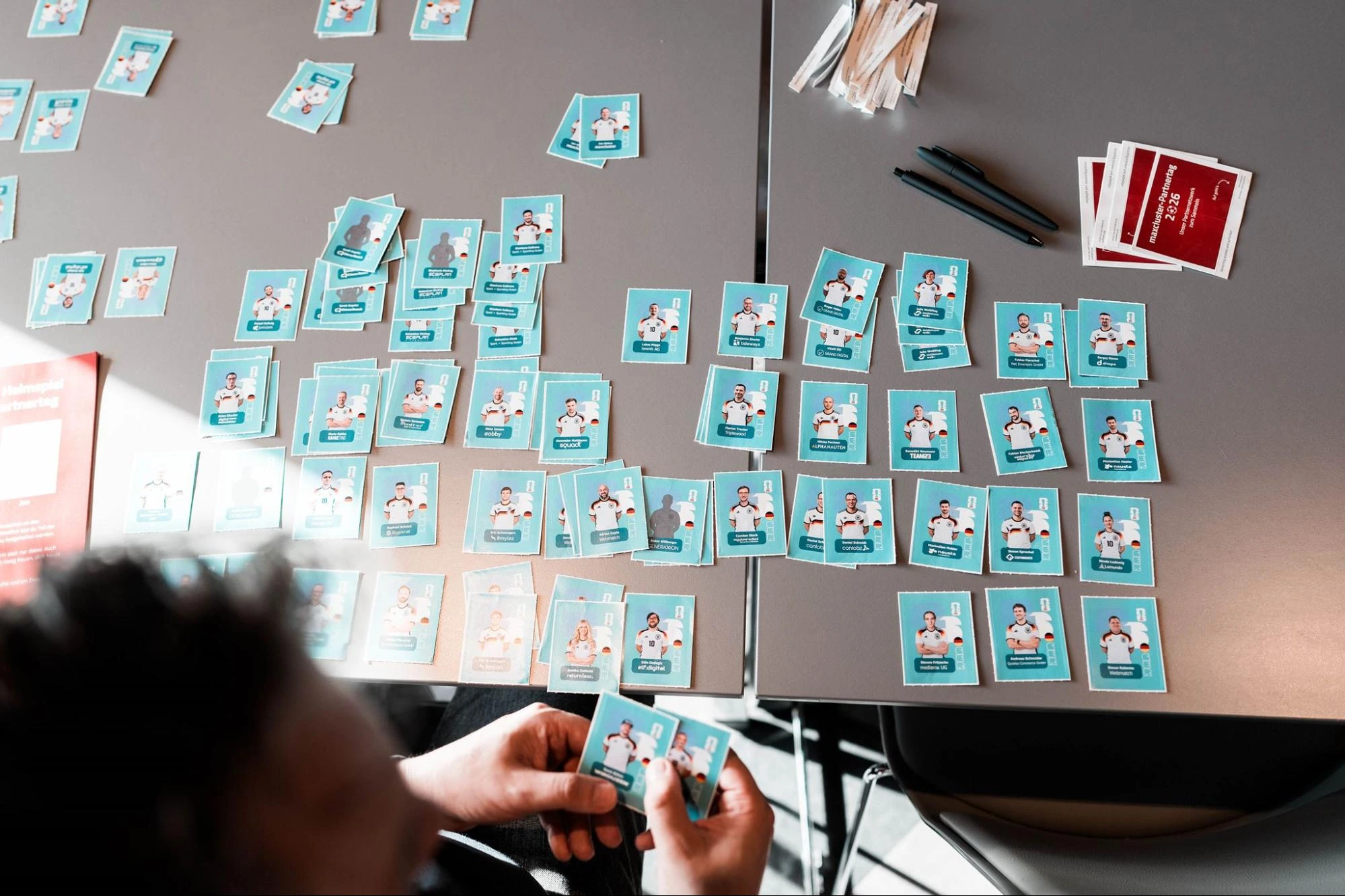 Person sammelt die Panini-Sticker der Teilnehmenden beim maxcluster-Partnertag 2026