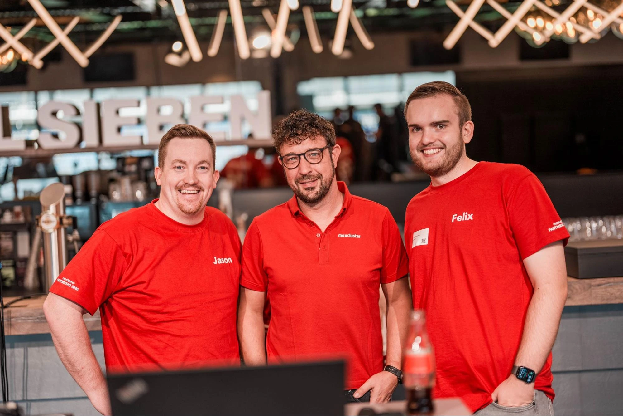 Drei Mitarbeiter von maxcluster beim Partnertag 2026 in der Home Deluxe Arena