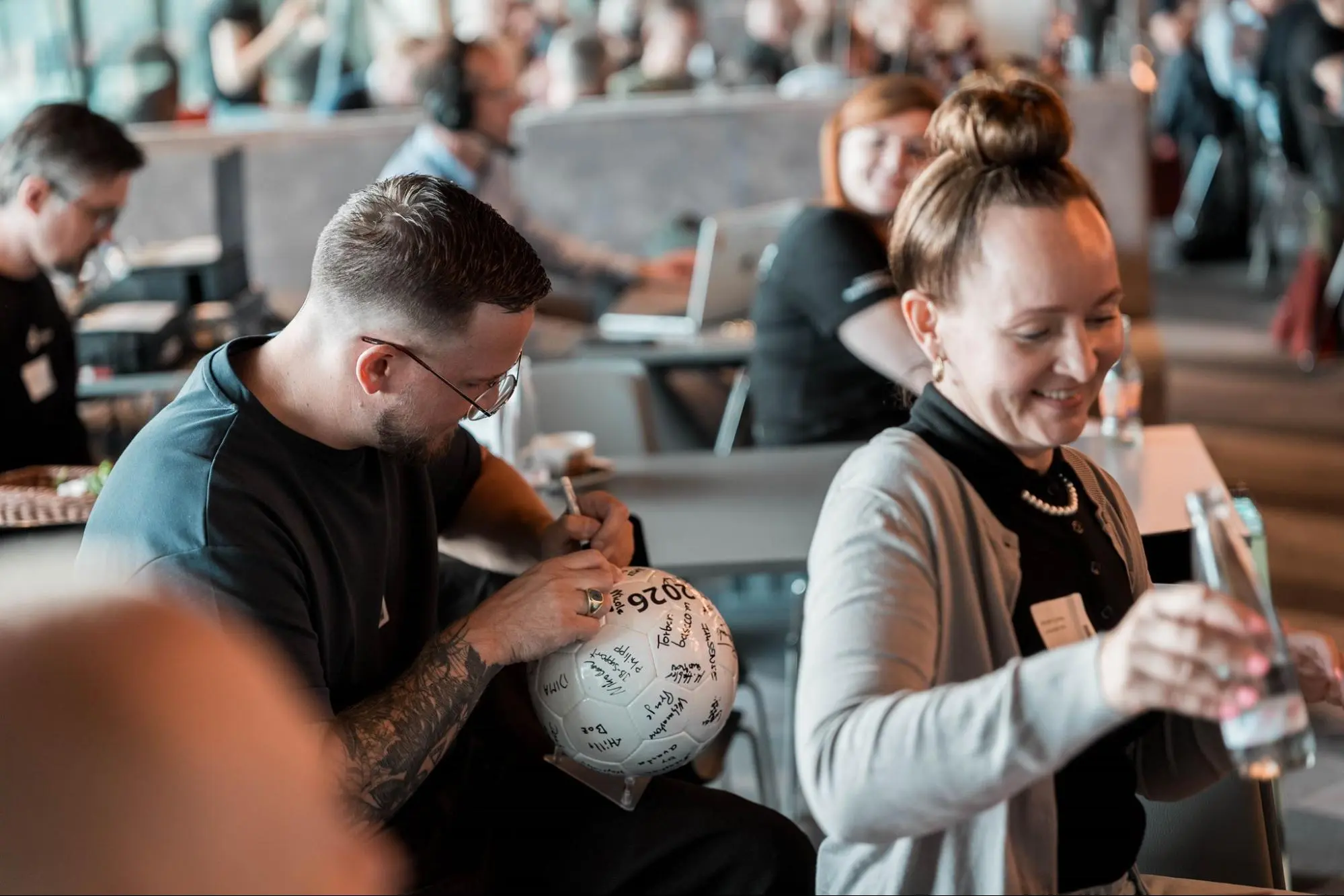Teilnehmende unterschreiben den Gästebuch-Fußball beim maxcluster-Partnertag 2026