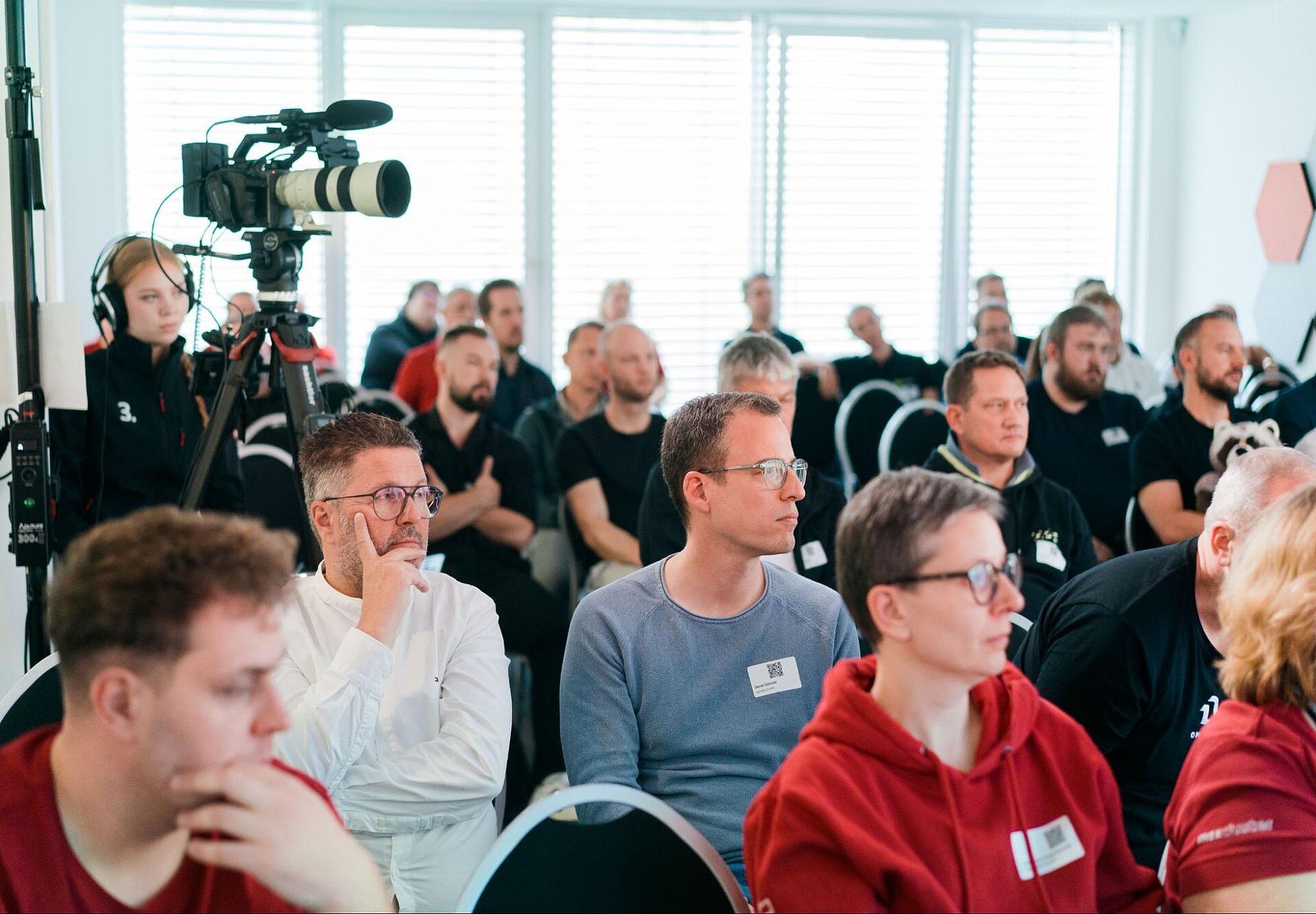 Teilnehmende des maxcluster-Partnertags 2025 verfolgen konzentriert die Vorträge im großen Konferenzraum.