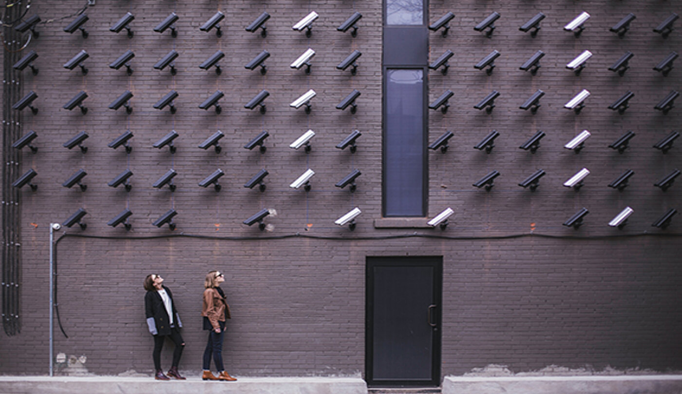 Two woman in front of a building, with a lot of cameras.
