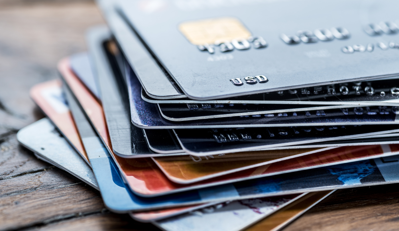 Stacked credit and debit cards on a wooden surface