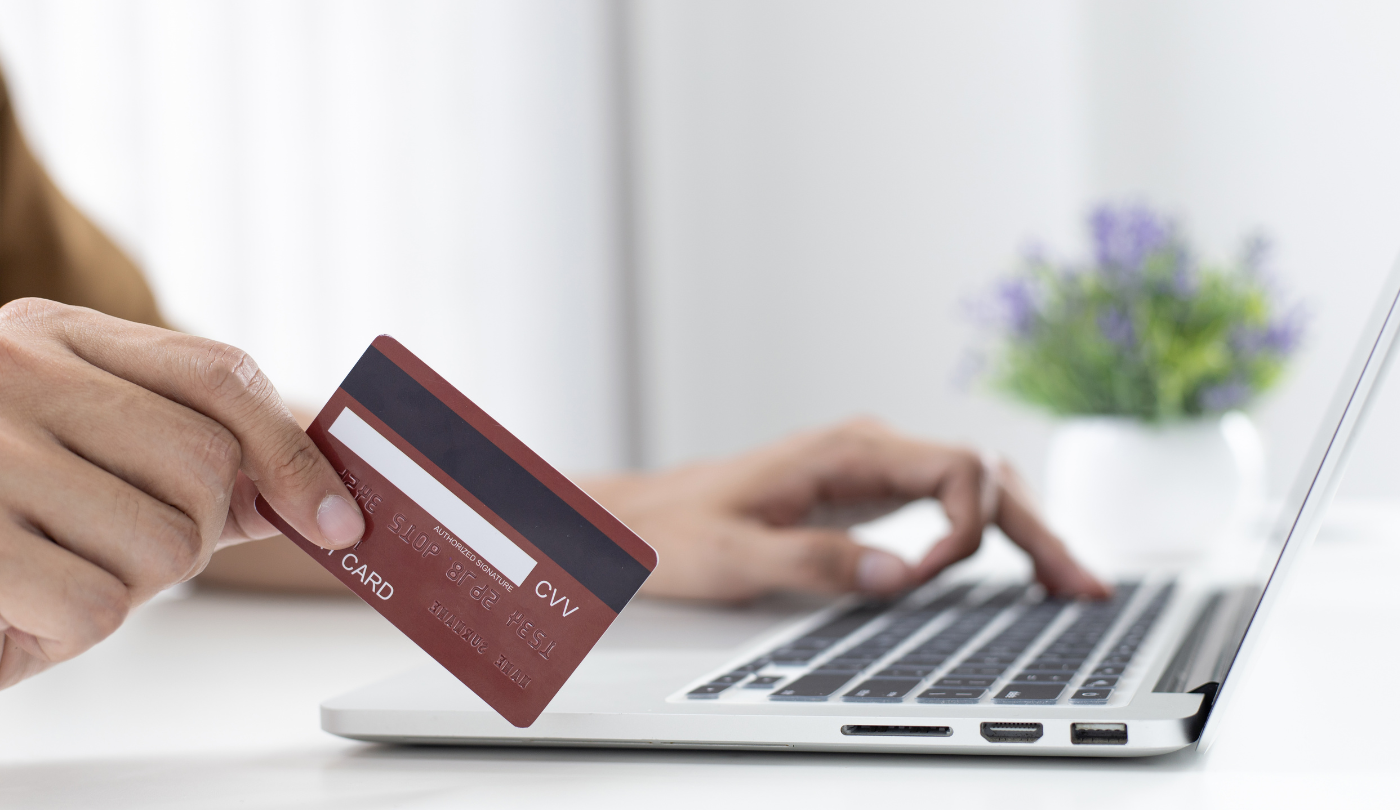 Person holding a credit card and entering data on a laptop