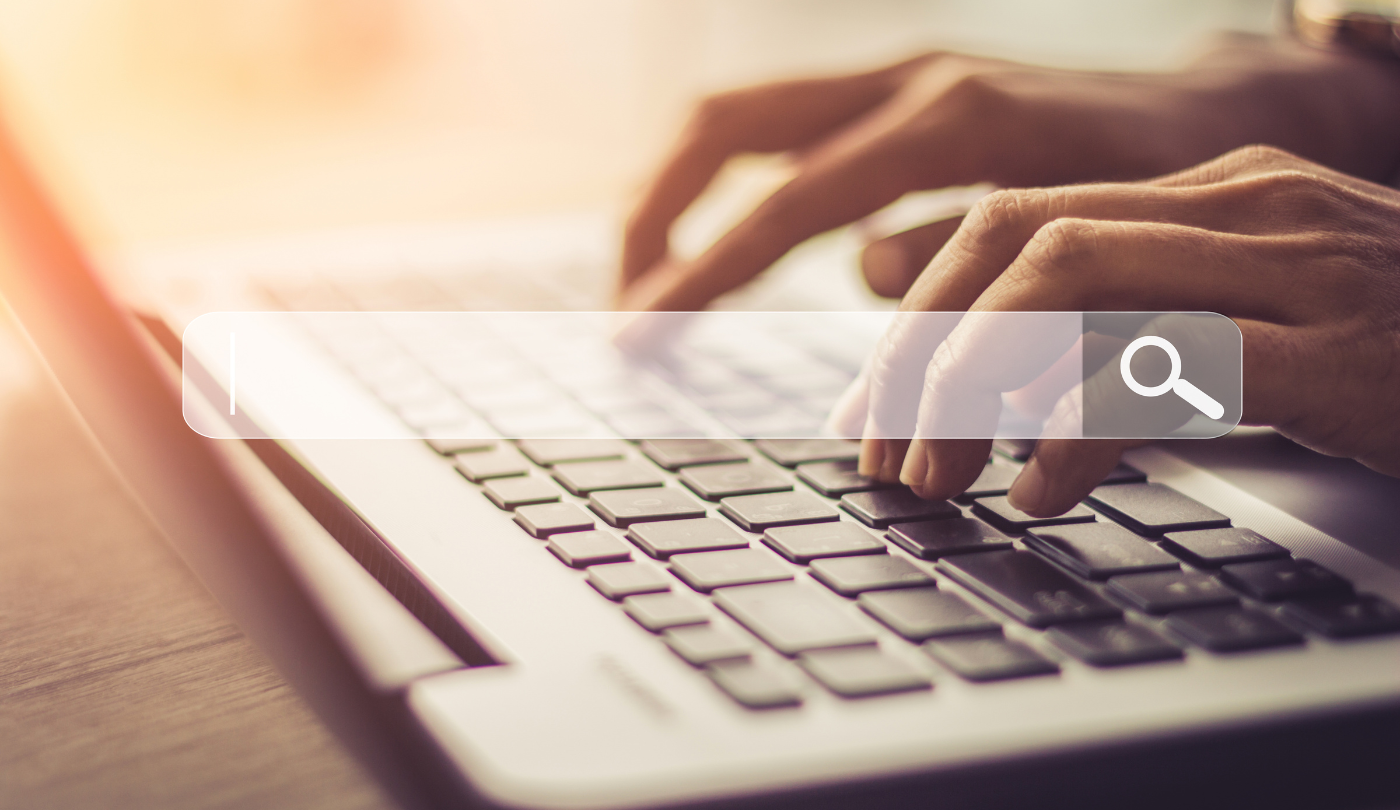 Nahaufnahme von Händen auf einer Laptop-Tastatur mit eingeblendeter Suchleiste – symbolisiert die moderne visuelle und multimodale Suche